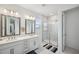 Bright bathroom featuring double sinks, modern vanity, tile floors, and glass shower with shower niche at 5103 San Martino Dr, Wesley Chapel, FL 33543