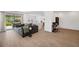 Spacious living room with gray sectional sofa, patio access, wood-look tile flooring, and a view of the kitchen and office at 5103 San Martino Dr, Wesley Chapel, FL 33543