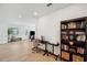 Open office space flowing into living area, featuring a black desk, rolling bookcase, and view of the living room at 5103 San Martino Dr, Wesley Chapel, FL 33543