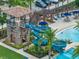 A detailed view of the pool area with a water slide, a stone tower, palm trees, and seating for relaxation at 5103 San Martino Dr, Wesley Chapel, FL 33543