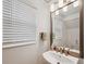 Stylish powder room featuring a pedestal sink, framed mirror, and window at 5103 San Martino Dr, Wesley Chapel, FL 33543