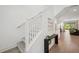 Elegant staircase with white railings and grey wood steps; hallway with console table and modern art at 5103 San Martino Dr, Wesley Chapel, FL 33543