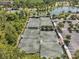 Aerial view of community tennis courts near a serene lake and lush trees, providing a tranquil setting for outdoor recreation at 5103 San Martino Dr, Wesley Chapel, FL 33543