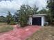 Modest one-story home with white exterior, black garage door, and red driveway at 6715 16Th N St, St Petersburg, FL 33702