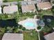 Birds eye view of community pool with lounge chairs, cabana and hot tub surrounded by beautiful landscaping and palm trees at 7714 Sailwinds Pass, Port Richey, FL 34668