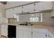 A kitchen with white cabinets, neutral countertops, black appliances, and a window view at 8110 Pond Shadow Ln, Tampa, FL 33635
