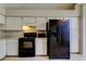 Efficient kitchen with white cabinets, laminate counters, black appliances and neutral tile flooring at 8110 Pond Shadow Ln, Tampa, FL 33635
