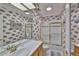Well-lit bathroom featuring a vanity, commode, shower-tub combo, and decorative wallpaper at 915 Symphony Isles Blvd, Apollo Beach, FL 33572