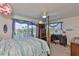 Bedroom view with ceiling fan, four poster bed, desk, and outside views through two large windows at 915 Symphony Isles Blvd, Apollo Beach, FL 33572