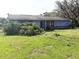 Exterior of a one story home with grass yard and overgrown landscaping at 9722 Kenton Rd, Wesley Chapel, FL 33545