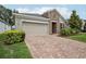 Attractive home featuring a brick driveway, two-car garage, and a meticulously kept lawn and garden at 10625 Cardera Dr, Riverview, FL 33578