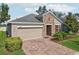 Desirable property showcasing a brick driveway, a two-car garage, and a beautiful lawn with lush plantings at 10625 Cardera Dr, Riverview, FL 33578