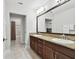 Bathroom with dual sinks, granite countertops, dark wood cabinets, and shower with tile surround at 11624 Calf Path Dr, Tampa, FL 33626