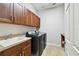 A modern laundry room features front loading washer/dryer, tile floors, storage cabinets and a utility sink at 11624 Calf Path Dr, Tampa, FL 33626