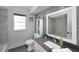 Modern bathroom with gray tiling, a sleek vanity, and a well-lit mirror at 12913 126Th Ter, Largo, FL 33774