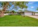 Charming single-story home featuring a lush green lawn, mature trees, and a two-car garage at 1398 Lemon St, Clearwater, FL 33756