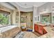 An elegant bathroom with a soaking tub, walk-in shower, granite counters, and natural light from a large window at 16124 Suncrest Shores Dr, Odessa, FL 33556