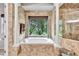 An elegant bathroom highlighting a soaking tub with a large window, dual columns, and a tiled shower at 16124 Suncrest Shores Dr, Odessa, FL 33556