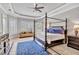A bedroom with a four-poster bed, blue accents and a large window with plantation shutters allowing ample natural light at 16124 Suncrest Shores Dr, Odessa, FL 33556