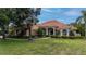 Charming, single-story home with a well-manicured lawn, lush landscaping, and a clay tile roof at 16124 Suncrest Shores Dr, Odessa, FL 33556