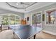 Game room featuring a ping pong table with backyard views through a large window and access to the screened porch at 16124 Suncrest Shores Dr, Odessa, FL 33556