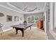 A spacious game room with a ping pong table, ceiling fan, and large window with a view of the manicured lawn at 16124 Suncrest Shores Dr, Odessa, FL 33556