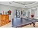 This game room with a dart board has access to the pool, an open space for indoor outdoor entertainment at 16124 Suncrest Shores Dr, Odessa, FL 33556