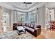 Bright living room featuring a large leather sofa, tray ceiling, and access to the outdoor living area at 16124 Suncrest Shores Dr, Odessa, FL 33556
