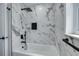 Modern tub/shower combo with marble tile, black fixtures, and a built-in niche at 1624 Chateau Dr, Clearwater, FL 33756