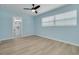 Light blue bedroom features wood floors, ceiling fan, and adjoining bathroom at 1624 Chateau Dr, Clearwater, FL 33756