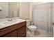 Cozy bathroom with a single sink vanity, toilet, and shower featuring patterned shower curtain at 18933 Sailors Delight Pass, Land O Lakes, FL 34638