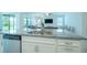 Kitchen island with stainless steel sink, granite countertops, white cabinets and stainless steel dishwasher at 18933 Sailors Delight Pass, Land O Lakes, FL 34638