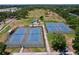 Aerial view of tennis courts and large green space with mature trees in a quiet community at 2152 74Th N St, St Petersburg, FL 33710