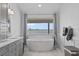 Serene bathroom featuring a standalone tub, double vanity, and a window with views of the water at 297 1St W St, Tierra Verde, FL 33715