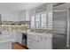 Well-lit, white kitchen featuring farmhouse sink, stainless steel appliances, and mosaic backsplash at 297 1St W St, Tierra Verde, FL 33715