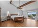Bright main bedroom featuring wood floors, ceiling fan, exposed beam, and sliding glass doors to a deck overlooking the water at 297 1St W St, Tierra Verde, FL 33715