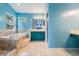 Bright bathroom featuring a soaking tub, blue walls, and a vanity with ample cabinet space at 3013 Crest Dr, Clearwater, FL 33759