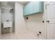 Functional laundry room with sink, tile flooring, and ample storage cabinets above at 3013 Crest Dr, Clearwater, FL 33759
