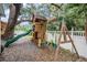 Backyard features a wooden playset with slide and swingset, surrounded by lush landscaping and a white picket fence at 3013 Crest Dr, Clearwater, FL 33759