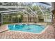 Backyard featuring a screened pool and spa surrounded by brick, providing ample space at 3013 Crest Dr, Clearwater, FL 33759
