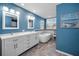 Stylish blue bathroom featuring double sinks, a soaking tub, and modern fixtures at 3047 Lake Padgett Dr, Land O Lakes, FL 34639