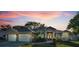 Charming single-story home with a two-car garage, lush landscaping, and a serene sunset backdrop at 3047 Lake Padgett Dr, Land O Lakes, FL 34639