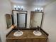 Bathroom featuring double sinks, granite countertops, decorative mirrors, and modern lighting fixtures at 3505 Tarpon Woods Blvd # K409, Palm Harbor, FL 34685