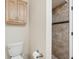 Bathroom featuring a toilet, wall cabinet, and a tiled walk-in shower with a decorative accent at 3505 Tarpon Woods Blvd # K409, Palm Harbor, FL 34685