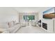 Bright living room with white furnishings, large windows, and a cozy fireplace at 3505 Tarpon Woods Blvd # K409, Palm Harbor, FL 34685