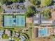 Aerial view featuring tennis courts, a pool, and clubhouse surrounded by lush greenery at 3956 Tarpon Pointe Cir, Palm Harbor, FL 34684