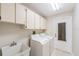 This laundry room features a utility sink, a washer, a dryer and cabinets for storage at 3956 Tarpon Pointe Cir, Palm Harbor, FL 34684