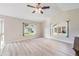 Light-filled living room with wood floors and views of the landscaped outdoors from large windows at 3956 Tarpon Pointe Cir, Palm Harbor, FL 34684