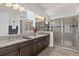 Spacious bathroom featuring double sinks, granite countertops, dark wood cabinets, and a glass-enclosed shower at 4195 Barletta Ct, Wesley Chapel, FL 33543