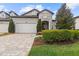 Charming home featuring a stone facade, well-maintained landscaping, and a brick driveway leading to the garage at 4195 Barletta Ct, Wesley Chapel, FL 33543